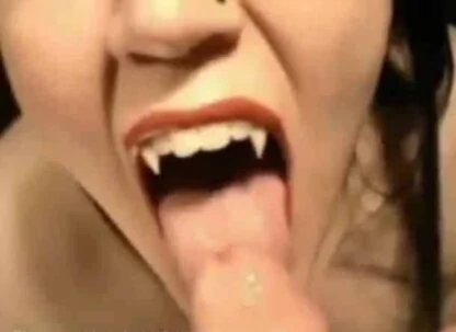 Fangs of a vampire about to bite a victim's cock