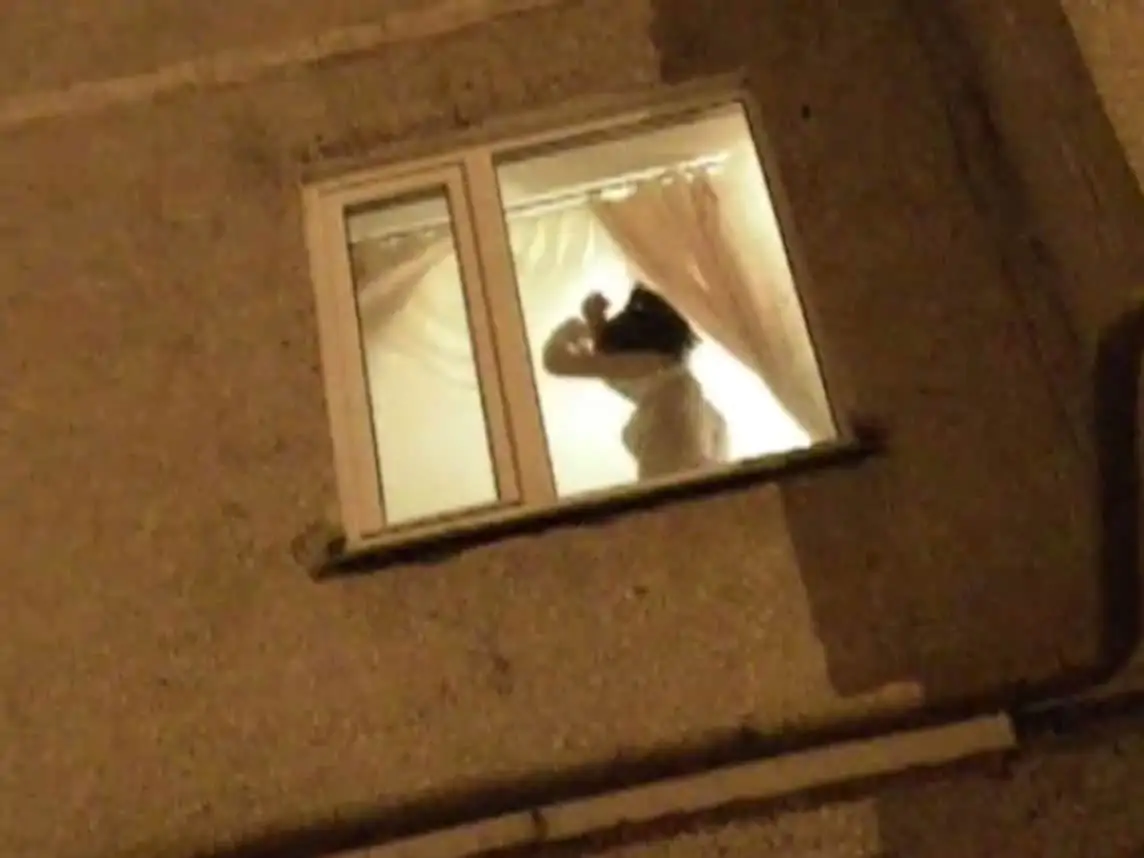 Woman Undressing in Window While Voyeur Watches from Outside